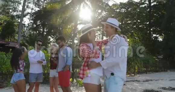 情侣在热带棕榈树公园拥抱人群共舞欢乐男女度假视频的预览图