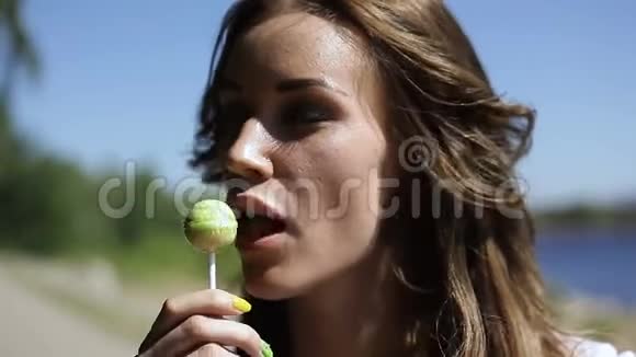 美丽的女孩在户外夏天吸棒棒糖视频的预览图