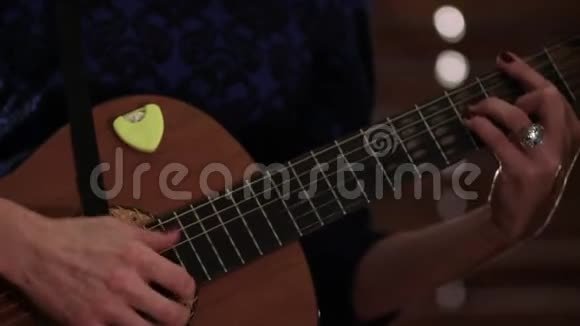 一个穿蓝色衣服的女孩在弹声吉他手放在乐器的弦上特写镜头视频的预览图