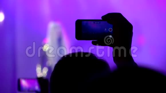 一个年轻人在智能手机上开演唱会视频的预览图