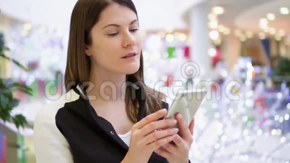商场里的女人用手机祝贺新年背景圣诞装饰视频的预览图