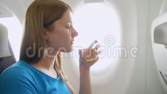 白天坐飞机的女人湍流中口渴的女性在靠近窗户的地方喝酒视频的预览图