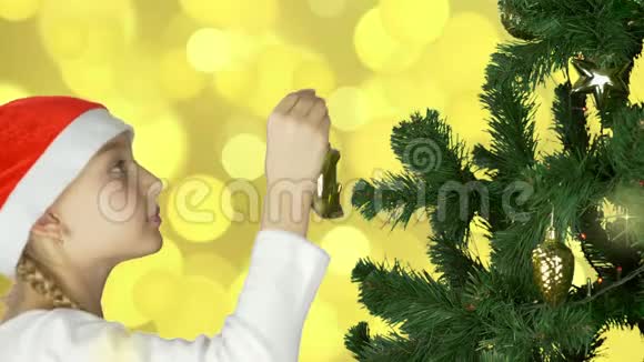 年轻的白种人女孩戴着红色圣诞帽用金色的球体装饰绿色的圣诞树准备庆祝一下视频的预览图