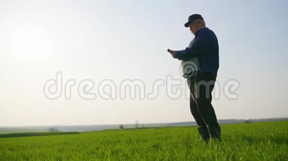 成熟的农民检查土壤和使用智能手机检查报告的农业领域视频的预览图