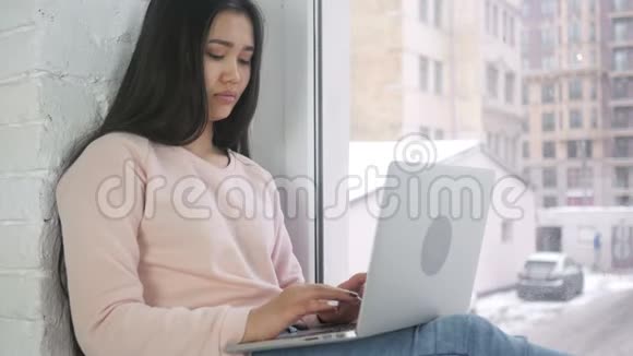 在电脑上工作的黑人妇女坐在窗边视频的预览图