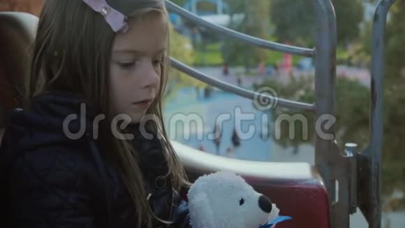 漂亮的女孩骑在旋转木马上微笑着但看起来很累因为她的泰迪在日落时在SLO莫视频的预览图