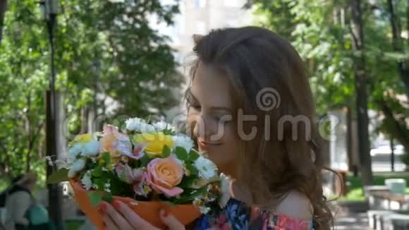 年轻的女人穿着一件漂亮的裙子走在公园里带着一束花特写美丽的微笑视频的预览图