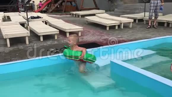 一个小男孩和一个十几岁的女孩在游泳池里玩充气圈视频的预览图