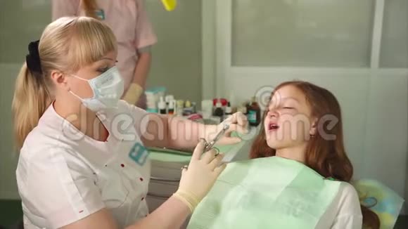 女牙医在牙科柜里给她的病人注射麻醉剂视频的预览图