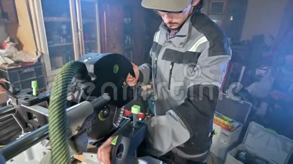 一个留着灰色工作服胡须的年轻人一个木匠在家里用一台圆形切割机工作视频的预览图