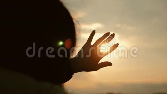 女孩在日落时用手看太阳视频的预览图