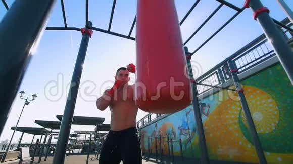 夏季户外慢动作带拳袋拳击的肌肉男视频的预览图