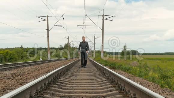 一个忧郁的人沿着铁轨走着视频的预览图