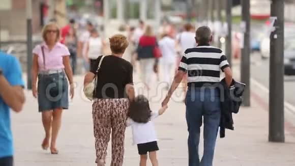 在城市街道上忙碌的行人中祖父母带着孩子散步视频的预览图