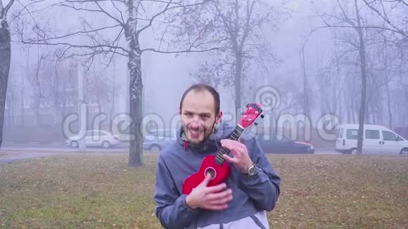 肖像帅哥在公园玩低音四弦琴音乐概念视频的预览图