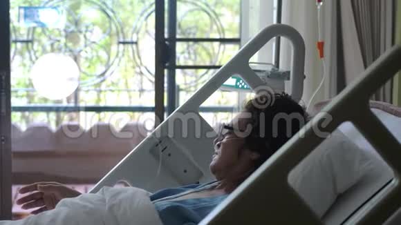 一位戴着眼镜的老年悲伤妇女躺在病床上她的氧气面罩在点滴下慢动作3840x2160视频的预览图