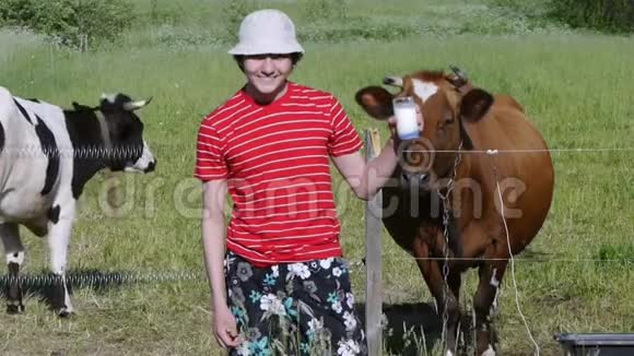 十几岁的孩子站在牧场上抱着一杯新鲜牛奶健康生活方式视频的预览图