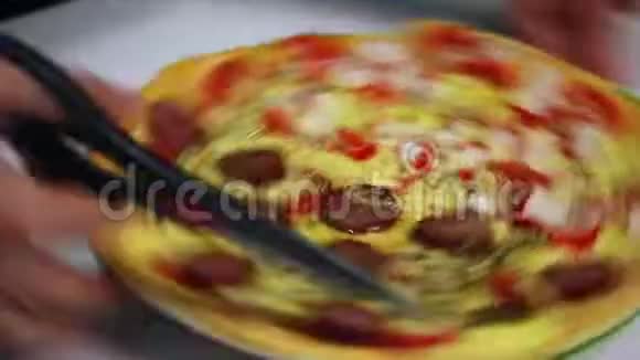 一个女人把煮熟的披萨切成薄片用剪刀视频的预览图