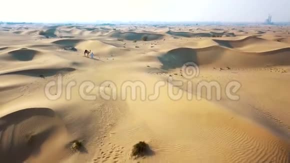 空中侦察无人机飞过沙漠贝都因人带着骆驼穿过沙漠视频的预览图