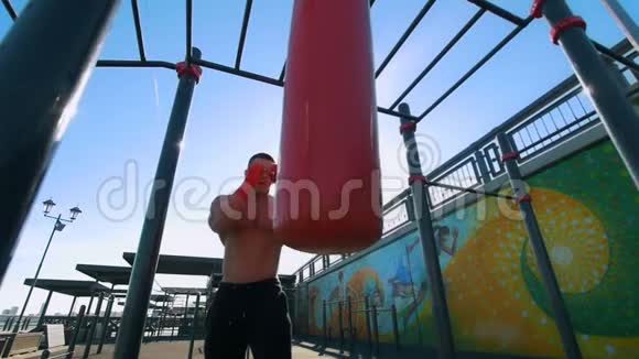夏季户外慢动作带拳袋拳击的肌肉男视频的预览图