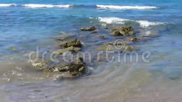海边的小海浪冲刷着海岸线附近的石头海水清澈心旷神怡视频的预览图