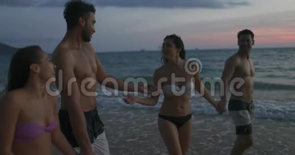 在暮光之城的夏日沙滩上聊天的人群朋友交流年轻的男女混血儿视频的预览图