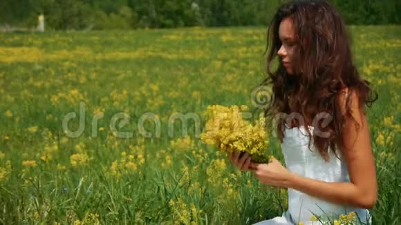 美丽的女人在绿色的田野里呼吸着黄花视频的预览图