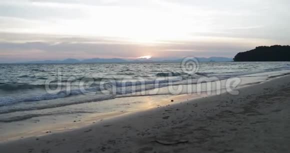 年轻夫妇在海中奔跑手挽手后景欢乐的男人和女人在夕阳下的海滩上观光视频的预览图