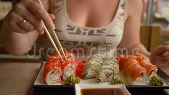 日本人吃女孩子手拿棍子把寿司蘸酱油在餐馆里视频的预览图