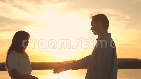 爱的男人和女人在湖底明亮的阳光下跳舞一对年轻夫妇在海滩日落时跳舞视频的预览图