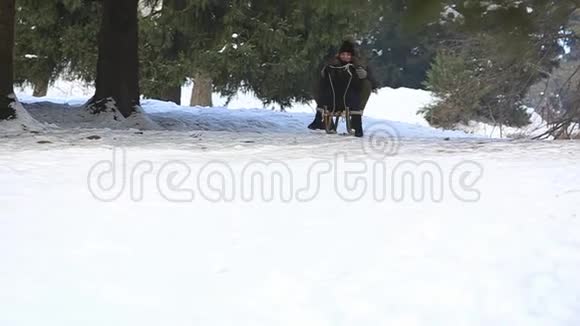 穿着黑色衣服的漂亮女孩骑在雪橇旁的雪山上雪橇视频的预览图