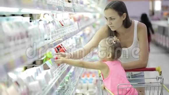年轻女子带着可爱的女儿在杂货店买酸奶视频的预览图