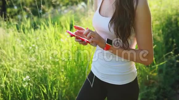 年轻女人用她的智能手机写信息绿色的草地背景视频的预览图