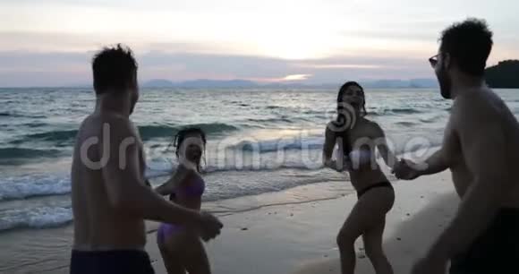 在日落时两位夫妇手牵着手在海上奔跑在度假时混合了一群人视频的预览图