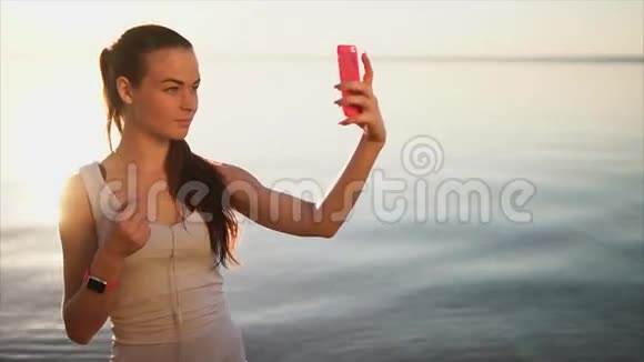 年轻漂亮的女人用她的智能手机做自拍照片视频的预览图