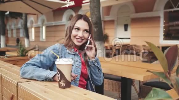 美丽的年轻快乐的女人坐在咖啡馆里打电话视频的预览图