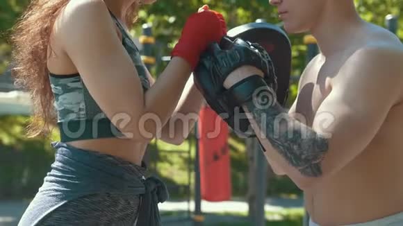 阳光明媚的一天年轻肌肉发达的男女在公园里打拳击视频的预览图