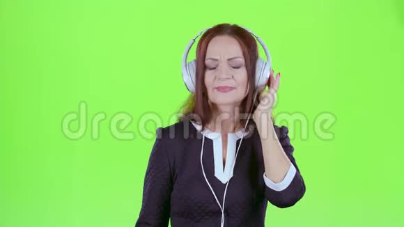 女士用耳机听音乐绿色屏幕视频的预览图