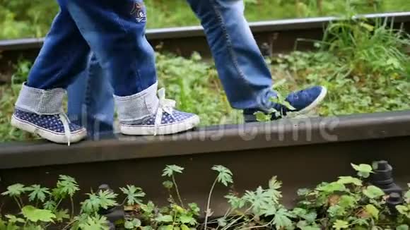 特写镜头腿在火车轨道上他抱着一个小孩走在铁路上视频的预览图
