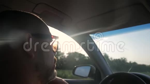 驾驶汽车的司机沿着道路行驶阳光明媚年轻英俊的男人开车的样子视频的预览图