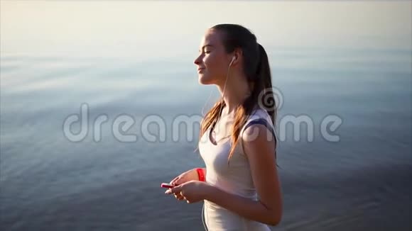 年轻快乐的女人用耳机听音乐她慢慢地跳舞视频的预览图