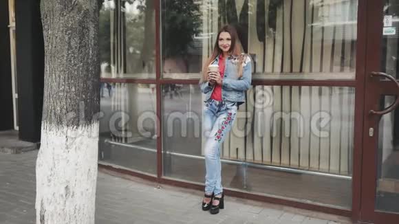 年轻的女人站在镜子前喝咖啡户外活动视频的预览图