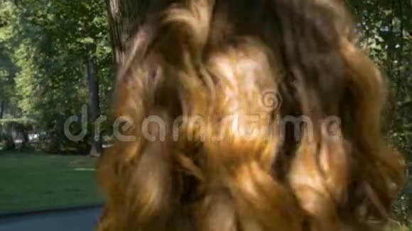 年轻漂亮的红头发的女人正在公园里散步视频的预览图