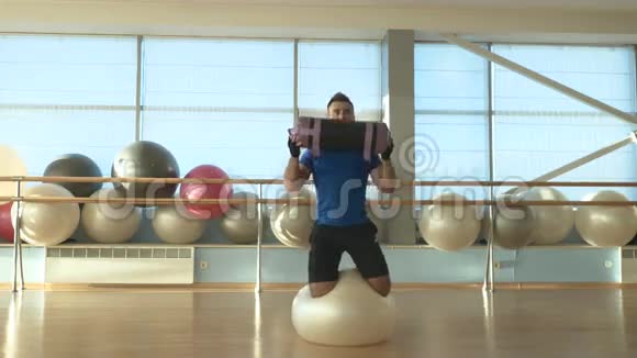 男子平衡的健身球和训练与重量健身房视频的预览图