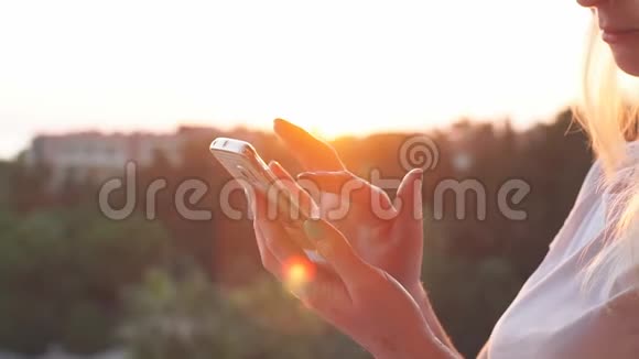 特写女性手在日落时使用智能手机慢动作视频的预览图
