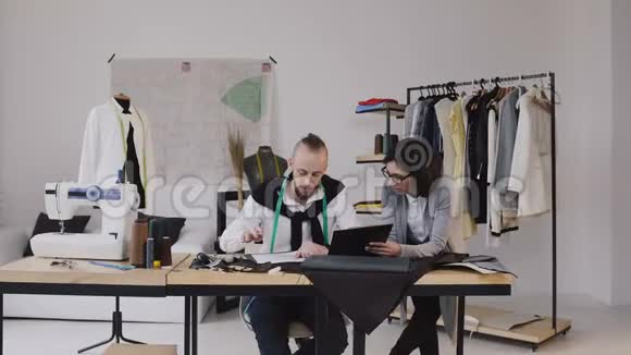 时装设计师在办公室工作使用不同的裁剪工具和衣服两位时装设计师男女视频的预览图