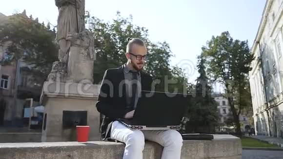 一个留着胡子的年轻人在电脑上工作喝咖啡视频的预览图