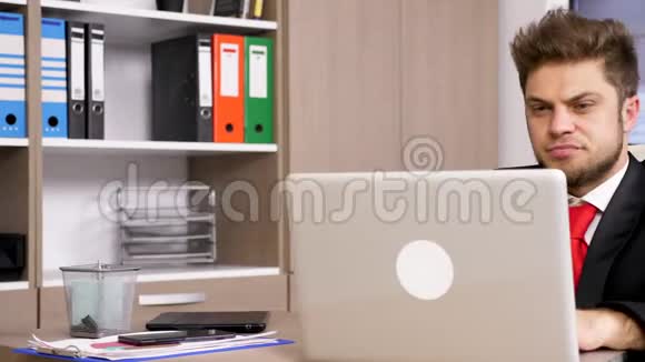 穿着正式西装的商人在笔记本电脑上打字面带微笑视频的预览图