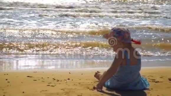 小女孩坐在沙滩上正在沙滩上画画视频的预览图