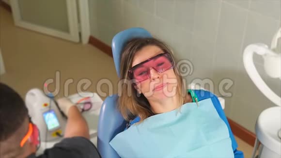戴防护橙色护目镜的女性病人坐在牙科沙发上视频的预览图